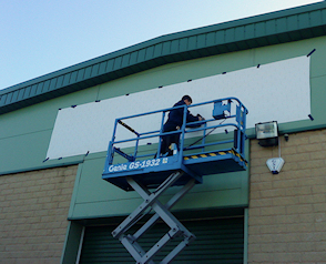 Flat cut acrylic lettering being fixed directly onto a metal cladded industrial unit.